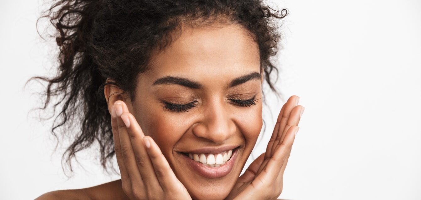 Happy young african woman posing isolated over white wall background.